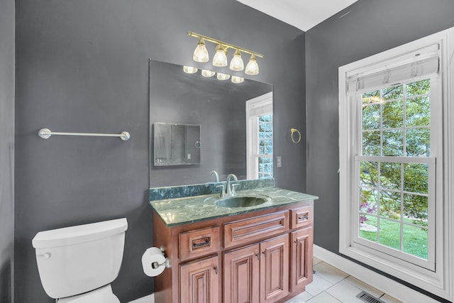 bathroom with toilet, tile patterned flooring, a wealth of natural light, and vanity