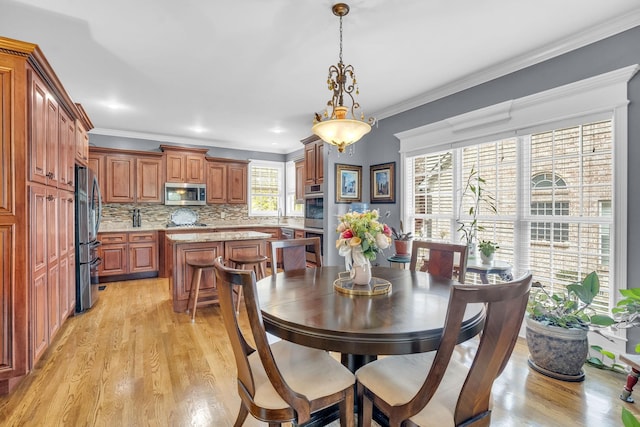 dining space with ornamental molding and light wood-type flooring