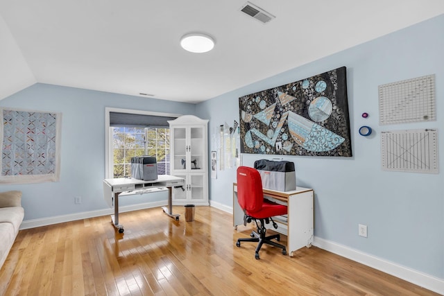 home office with light wood finished floors, visible vents, baseboards, and vaulted ceiling