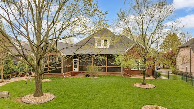 back of house featuring a sunroom, fence, and a lawn