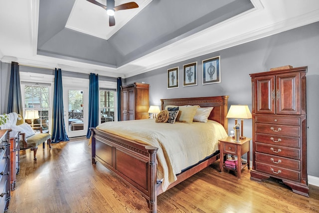 bedroom featuring a tray ceiling, light wood-type flooring, a ceiling fan, and ornamental molding