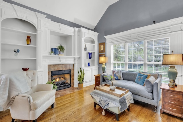 living area with built in shelves, light wood finished floors, and lofted ceiling