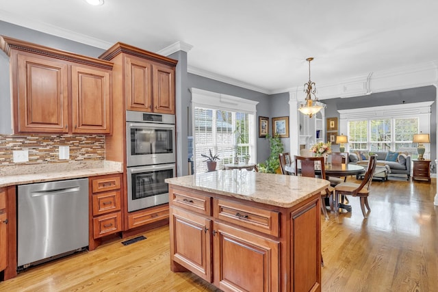 kitchen featuring ornamental molding, light stone counters, light wood-style floors, brown cabinets, and stainless steel appliances
