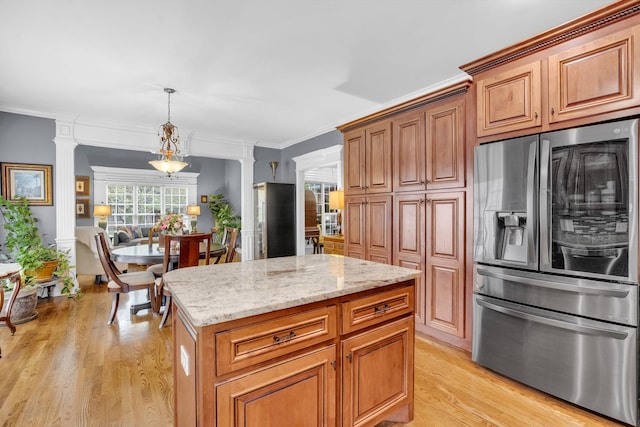 kitchen featuring light wood-type flooring, ornamental molding, stainless steel refrigerator with ice dispenser, light stone countertops, and decorative columns