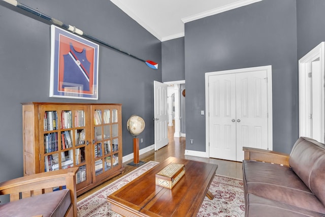 living room featuring ornamental molding, baseboards, a towering ceiling, and wood finished floors