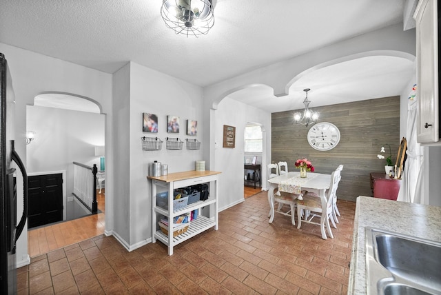 116 Dave Dr, Clarksville, TN 37042 - dining area with an inviting chandelier, a textured ceiling, arched walkways, brick floor, and wooden walls