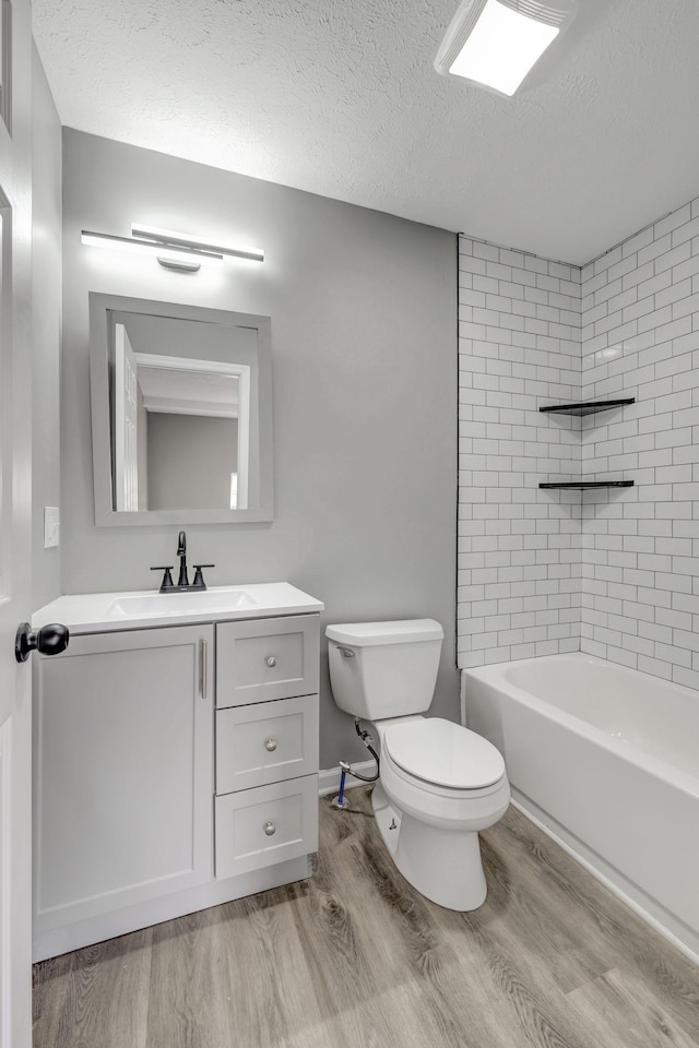 full bathroom featuring vanity, a textured ceiling, toilet, and wood finished floors