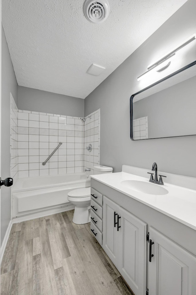 full bathroom with visible vents, toilet, a textured ceiling, vanity, and wood finished floors