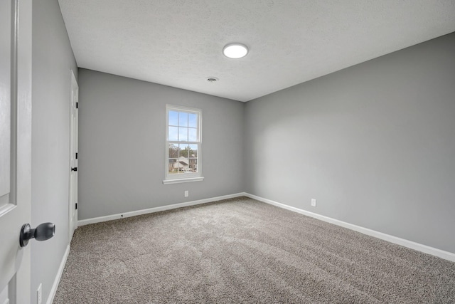 carpeted spare room with baseboards and a textured ceiling