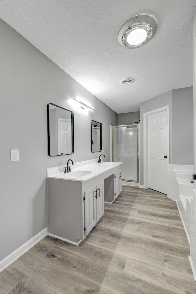 full bathroom featuring visible vents, a sink, a stall shower, and wood finished floors