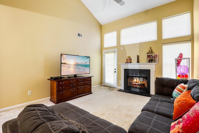 living room with visible vents, a wealth of natural light, a ceiling fan, a fireplace with flush hearth, and light colored carpet