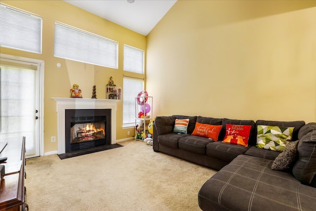 living area featuring baseboards, high vaulted ceiling, carpet flooring, and a fireplace with flush hearth