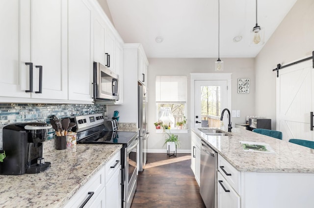 kitchen with dark wood-style flooring, white cabinets, a barn door, stainless steel appliances, and a sink
