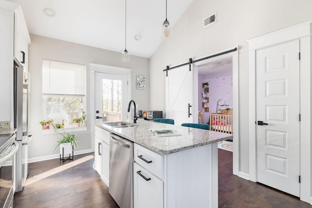 kitchen with pendant lighting, visible vents, a barn door, a sink, and stainless steel appliances