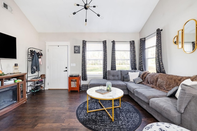 living area with an inviting chandelier, visible vents, vaulted ceiling, and wood finished floors