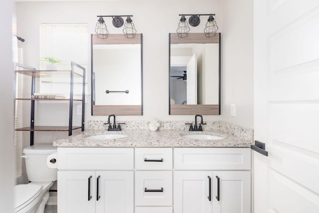bathroom with double vanity, a sink, and toilet