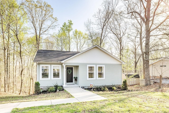 view of front of house with a front yard and a shingled roof