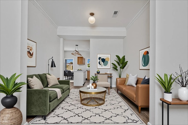 living room with crown molding, baseboards, visible vents, and wood finished floors