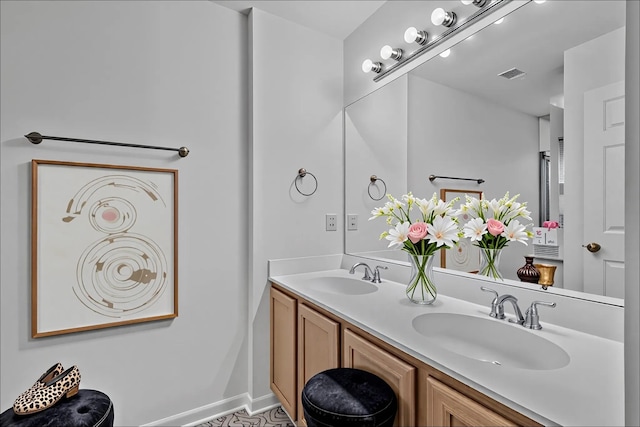 full bathroom with double vanity, baseboards, visible vents, and a sink