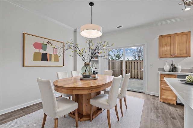 dining space with visible vents, ornamental molding, light wood-style flooring, and baseboards