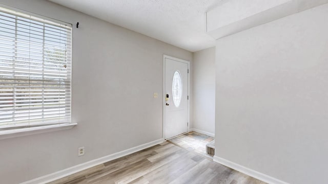 entrance foyer with baseboards, wood finished floors, and a textured ceiling
