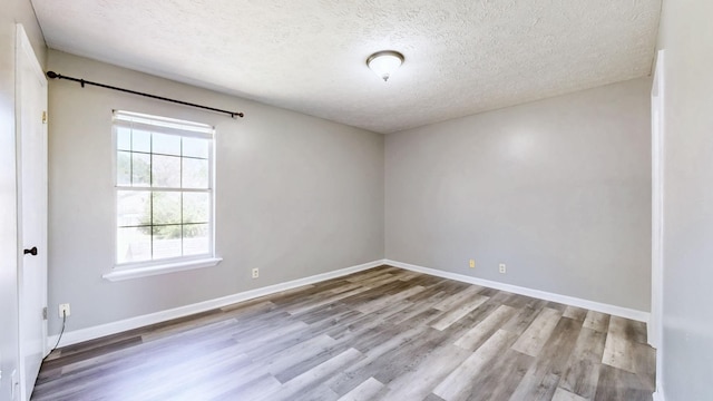 unfurnished room with baseboards, wood finished floors, and a textured ceiling