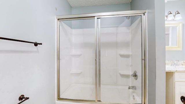 full bathroom with vanity, a shower with door, and a textured ceiling