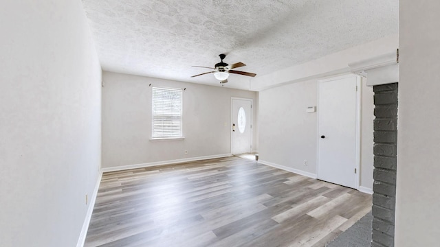 interior space with baseboards, a textured ceiling, wood finished floors, and ceiling fan
