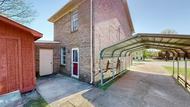 view of property exterior featuring aphalt driveway, brick siding, and a detached carport