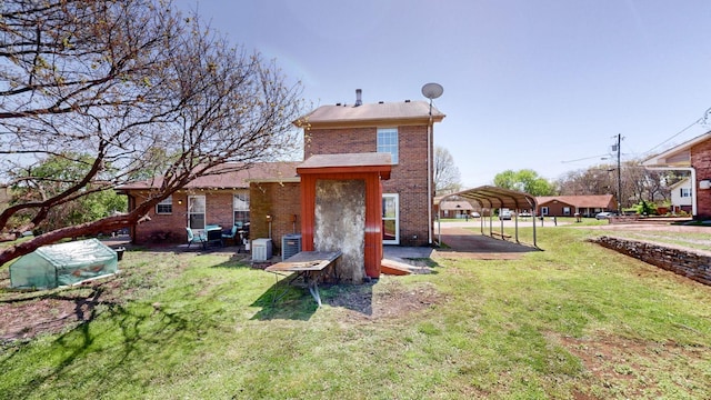 rear view of house featuring brick siding, central AC unit, a lawn, and a carport