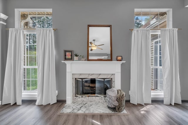 living area with wood finished floors, a high end fireplace, and baseboards