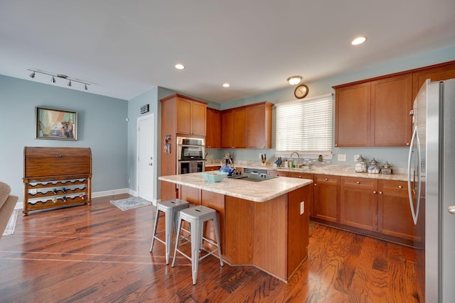 kitchen featuring a sink, dark wood finished floors, recessed lighting, stainless steel appliances, and a kitchen island