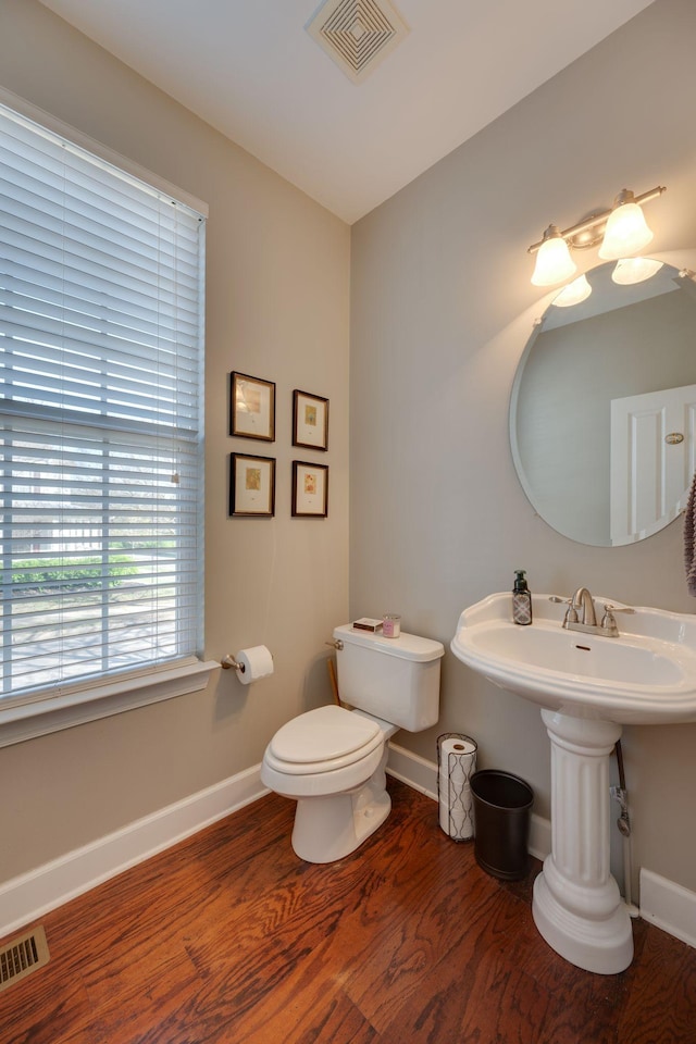 half bathroom with wood finished floors, baseboards, and visible vents