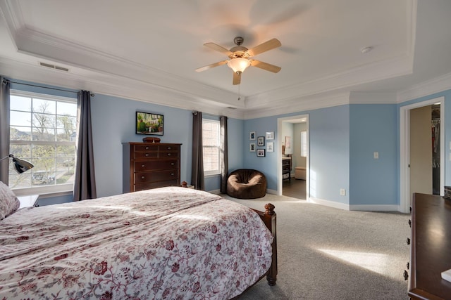 carpeted bedroom featuring baseboards, crown molding, visible vents, a tray ceiling, and ceiling fan