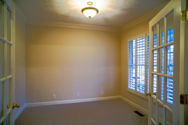 unfurnished room featuring a textured ceiling, visible vents, carpet, and plenty of natural light