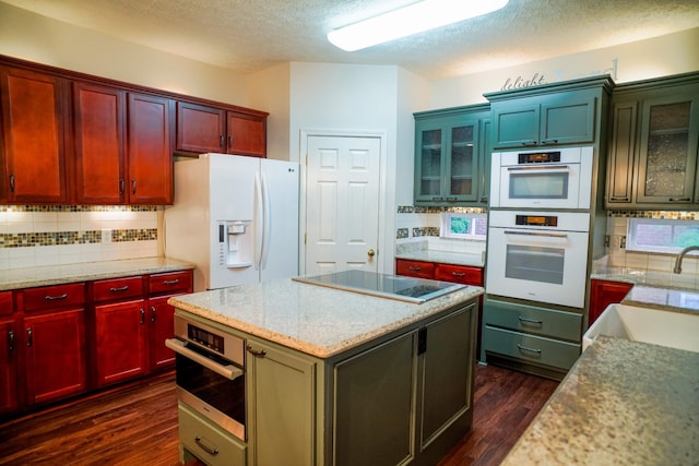kitchen featuring dark wood-type flooring, white appliances, a center island, and tasteful backsplash