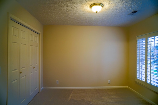 unfurnished bedroom featuring a closet, carpet, baseboards, and a textured ceiling