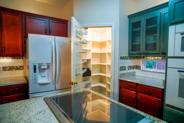 kitchen featuring tasteful backsplash, dark brown cabinets, and white appliances