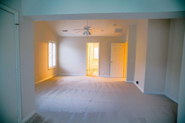carpeted spare room featuring visible vents, baseboards, and a ceiling fan