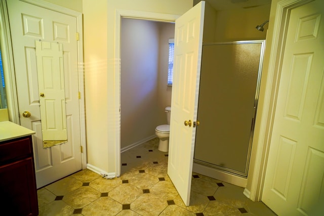 bathroom featuring a shower stall, vanity, toilet, tile patterned floors, and baseboards