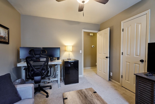 office area featuring baseboards, a ceiling fan, and light carpet
