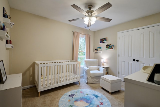 bedroom with a closet, baseboards, a ceiling fan, and a crib