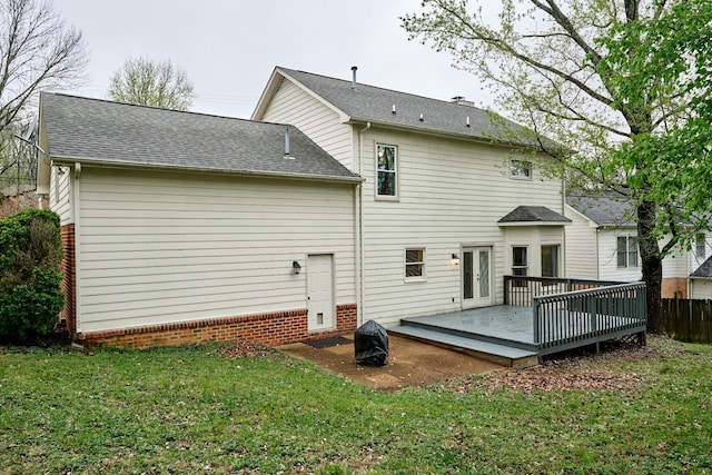 back of property with a yard, a shingled roof, fence, and a deck