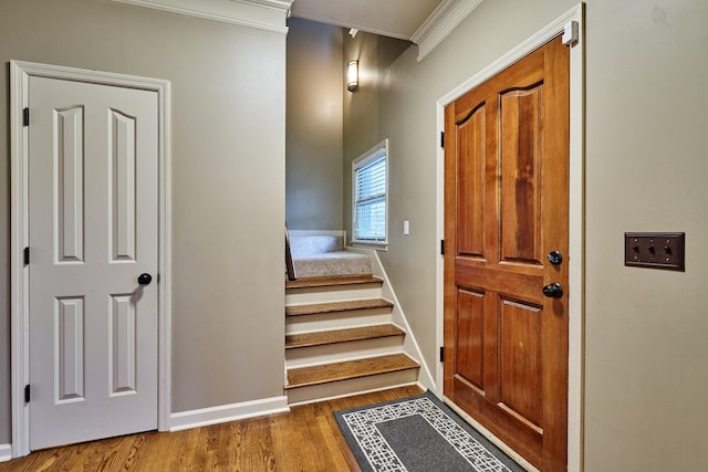 foyer with stairway, baseboards, crown molding, and wood finished floors