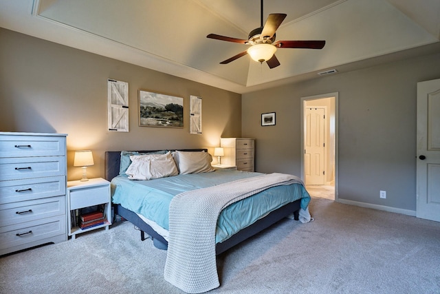 carpeted bedroom featuring a tray ceiling, baseboards, a ceiling fan, and visible vents