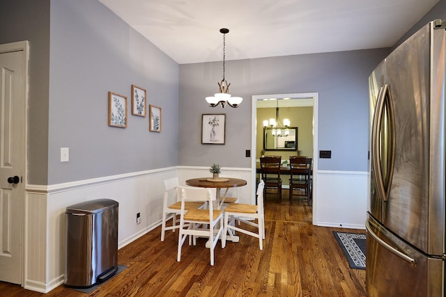 dining room featuring wood finished floors, a notable chandelier, and a wainscoted wall