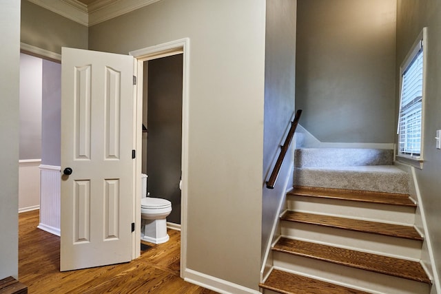 staircase featuring ornamental molding, baseboards, and wood finished floors