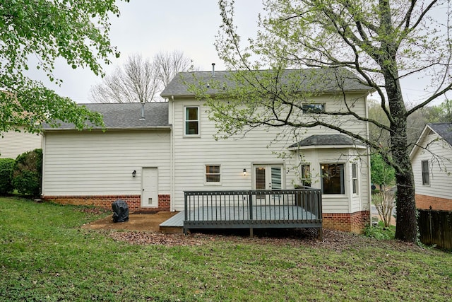 back of house featuring a shingled roof, a wooden deck, fence, and a lawn