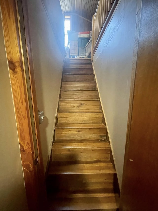 stairway featuring wood-type flooring and vaulted ceiling