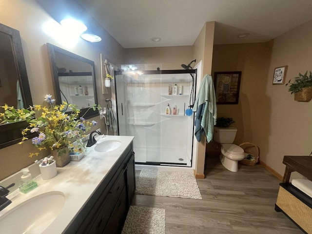 bathroom with a sink, a shower stall, double vanity, and wood finished floors
